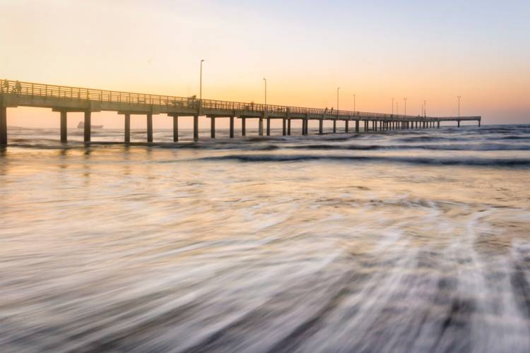 Aransas-Princess-Area-Guide Long Exposure of Waves Washing on Shore by Port Aransas Pier at Sunset Near Aransas Princess Resort