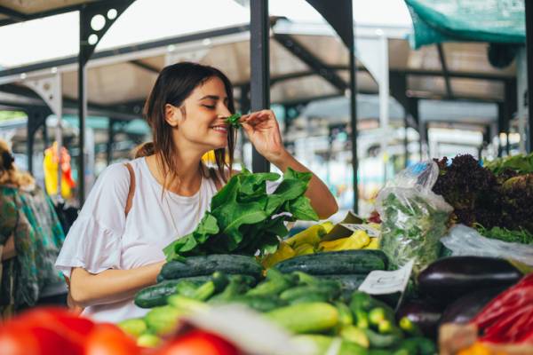 young woman smelling fresh basil at a farmers market