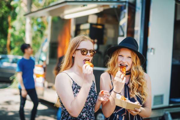 two redhead girls eating food from a food truck