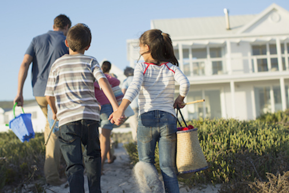 Brother and sister holding hands on beach path