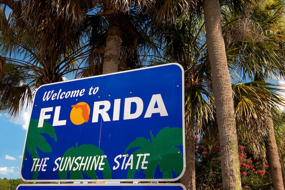 Welcome to Florida sign with palm trees in background