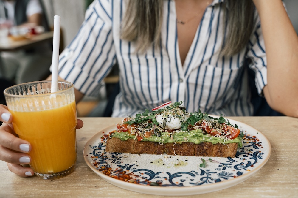 woman having breakfast with avocado toast and orange juice, healthy breakfast