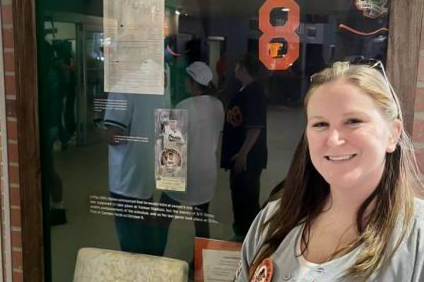 woman posing in front of a display wall for an athlete's memorabilia 