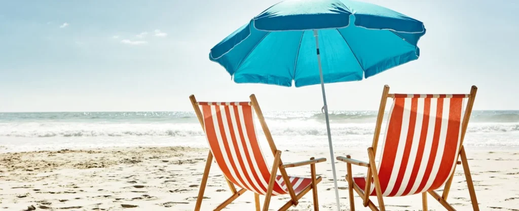 Still life shot of two deck chairs under an umbrella on the beach
