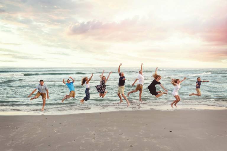 family jumping at holden beach