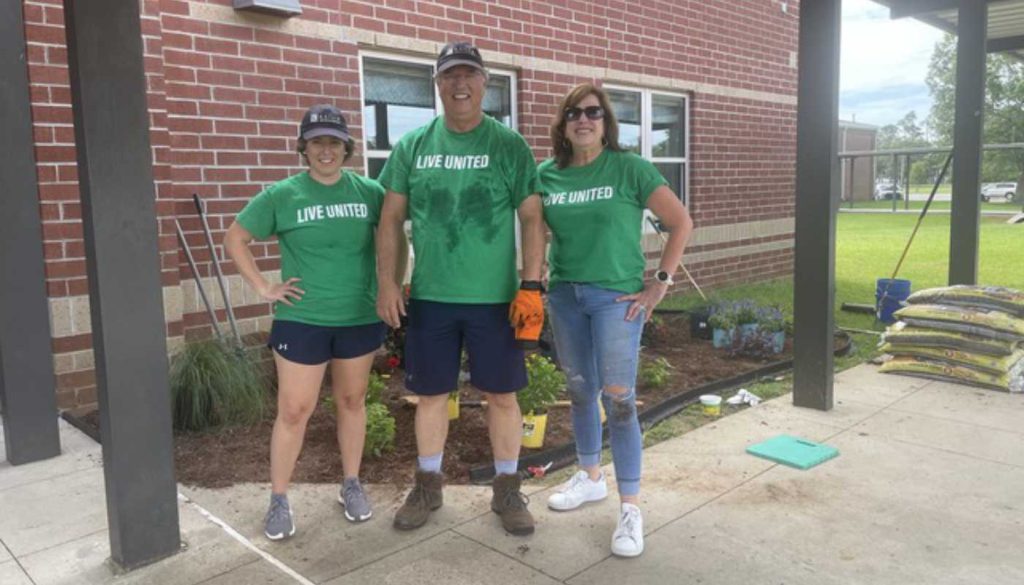 owner of kaiser vacation rentals and two employees in front of area where they planted flowers at elementary school