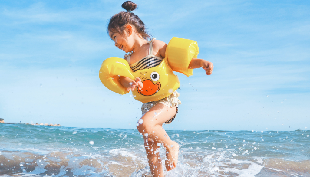 young girl smiling while playing along the shoreline