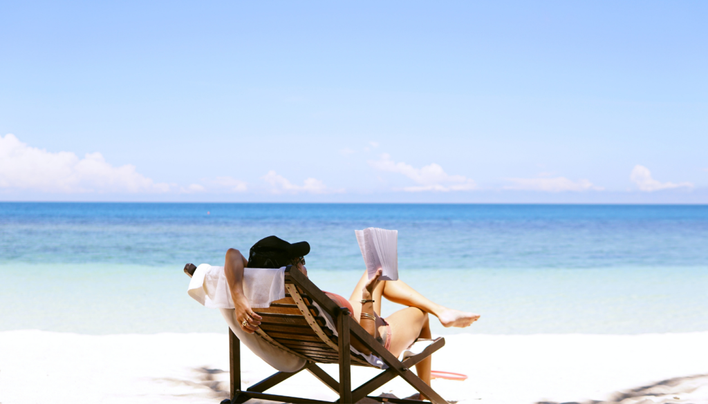 girl sitting in beach chair on beach reading a book