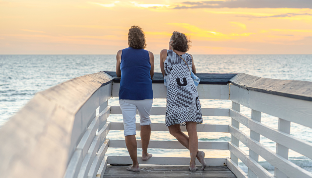 two women on boardwalk during summer looking at the beach