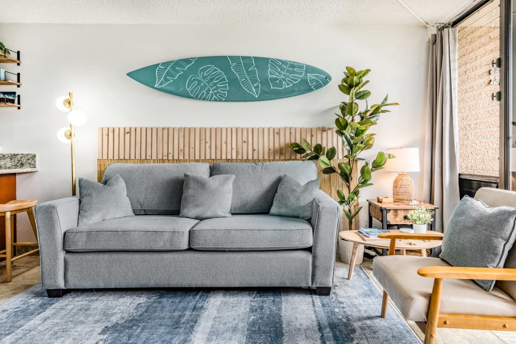 Living room in a Perch-managed Maui condo with a sofa, coastal art and lanai doors