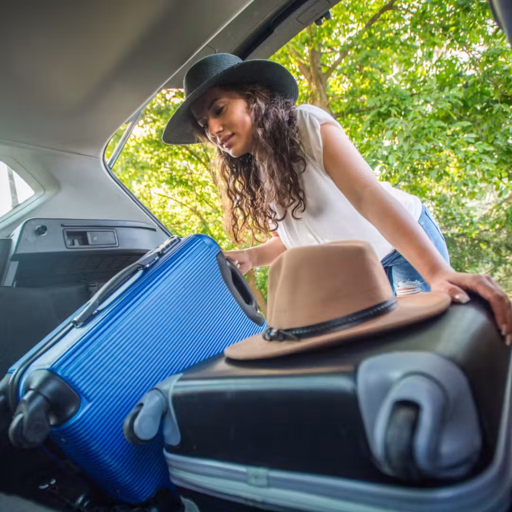 A woman packing suitcases into the back of a vehicle