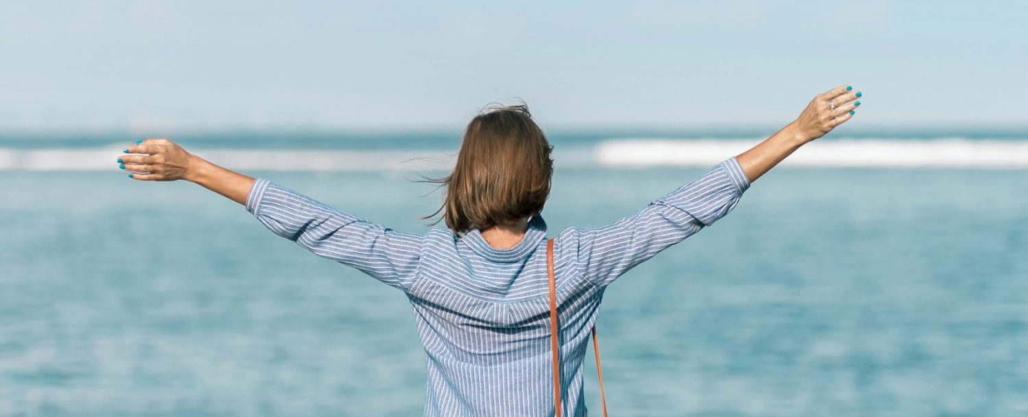 woman with arms spread to the ocean