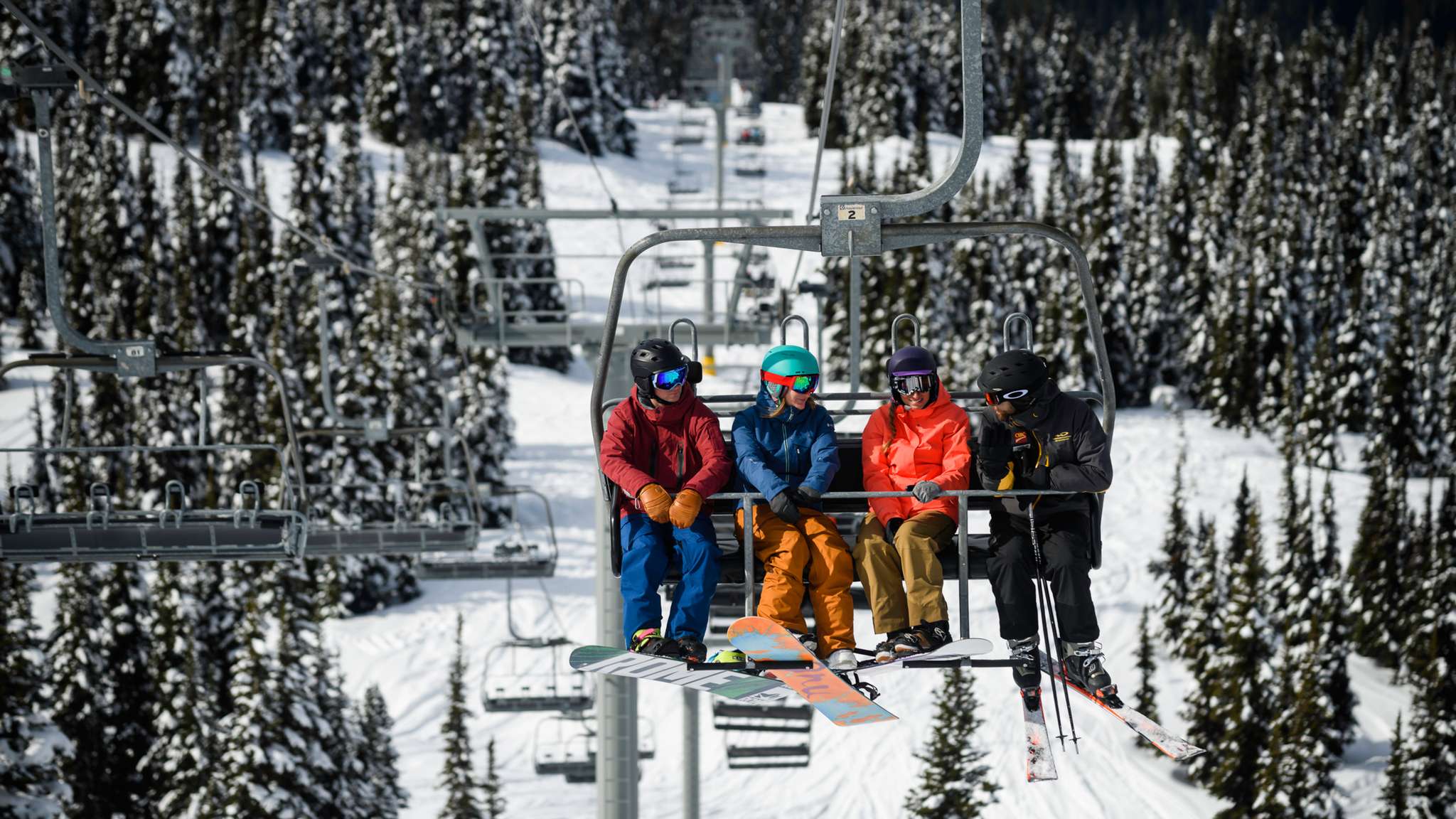 Skiers riding the lift up Whistler Blackcomb on a clear winter day